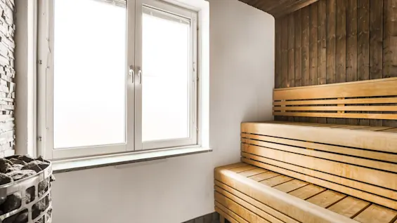 Valoisa saunahuone puupenkeillä, ikkunalla ja kivikiukaalla, tarjoten rentoutumista Comfort Hotel Linköping Cityssä.