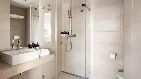 A modern and clean bathroom at Farris Bad in Larvik, featuring a spacious walk-in shower and a sleek vanity with a sink.
