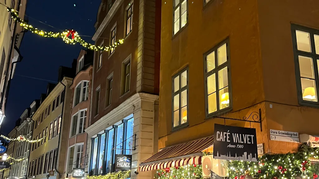 Folk der går langs en hyggelig gade i byen pyntet med julebelysning om aftenen