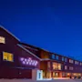 Punainen huvila, jossa on loistavat ikkunat ja neonmerkki "FUNKEN LODGE", sijaitsee hämärän taivaan alla vuoren ja kuunsirpun taustalla.