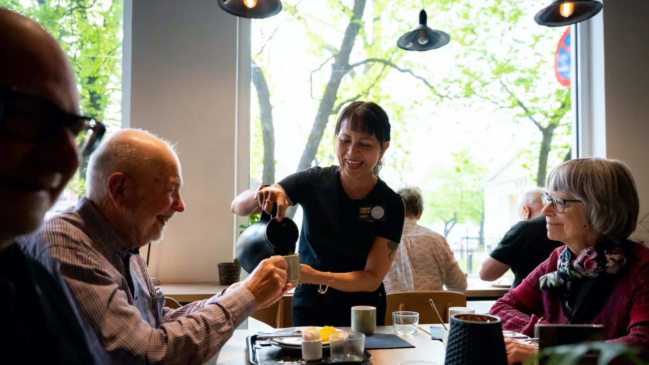 Kvinna häller upp kaffe till hotellgäster.