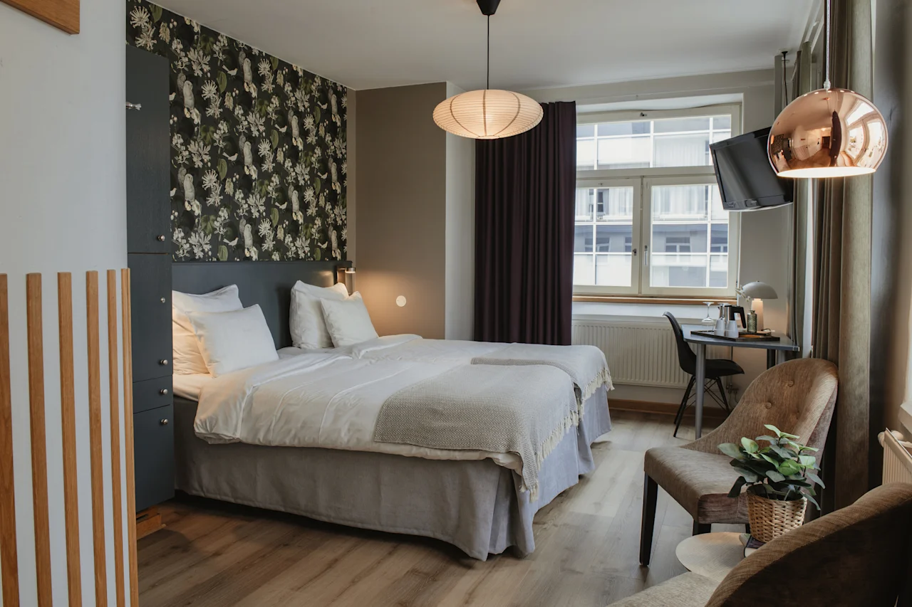 A cozy and inviting hotel room at Home Hotel Uppsala with two comfortable beds, a work desk, and a seating area.