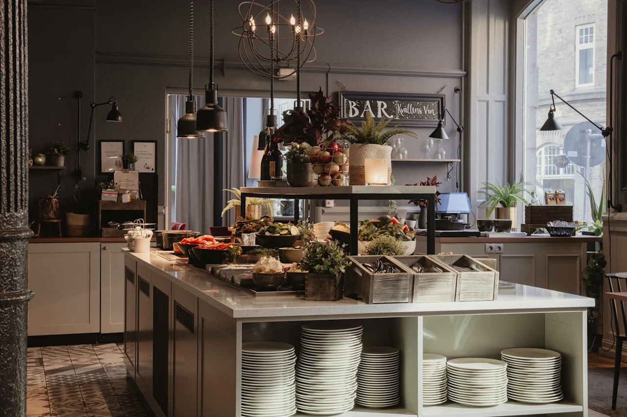 En innbydende buffet med et utvalg av ferske retter og pent stablede tallerkener, klare for gjester. Et skilt sier BAR Kvallens Vin.