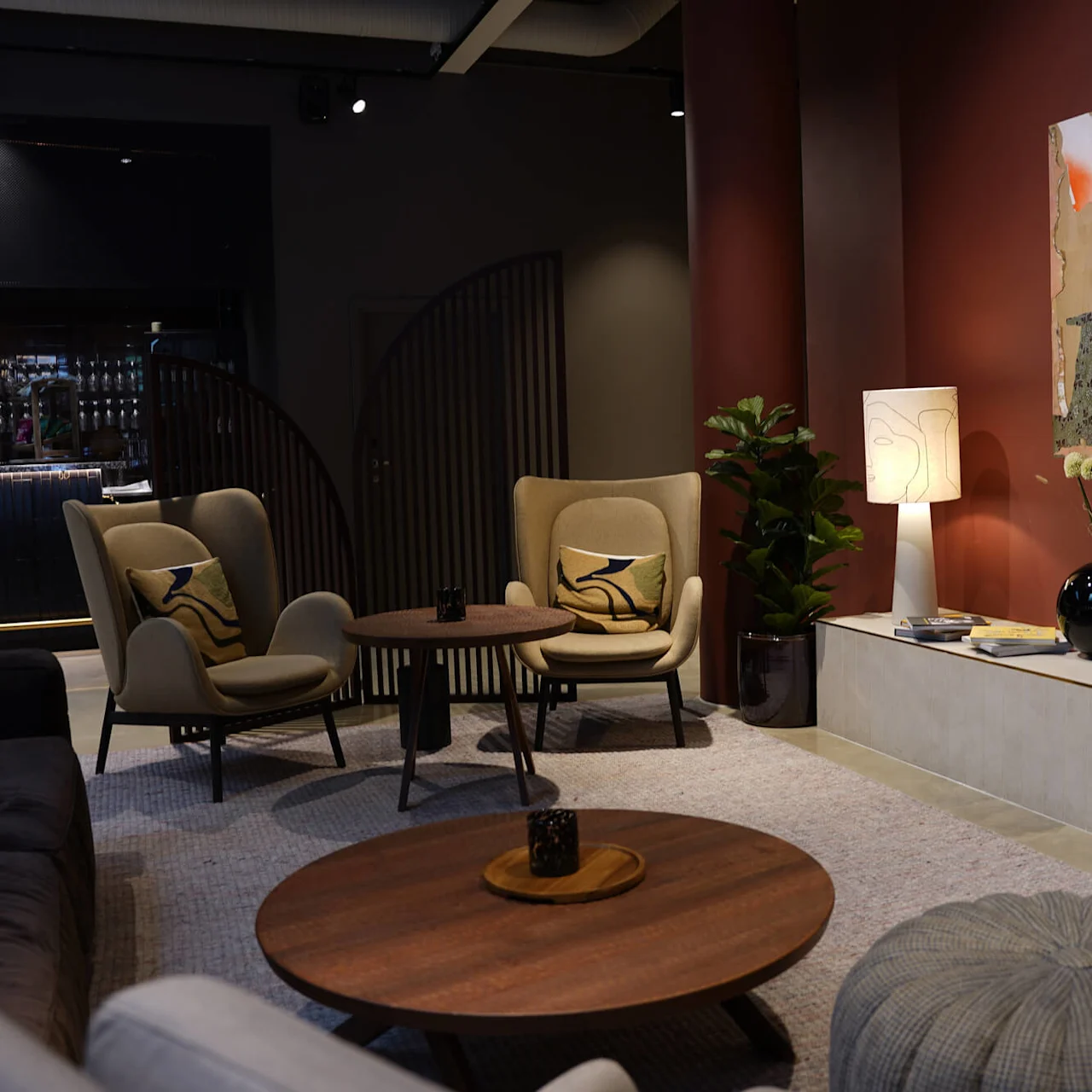 A modern lounge area with stylish furniture under warm lighting, creating a cozy atmosphere near a bar.