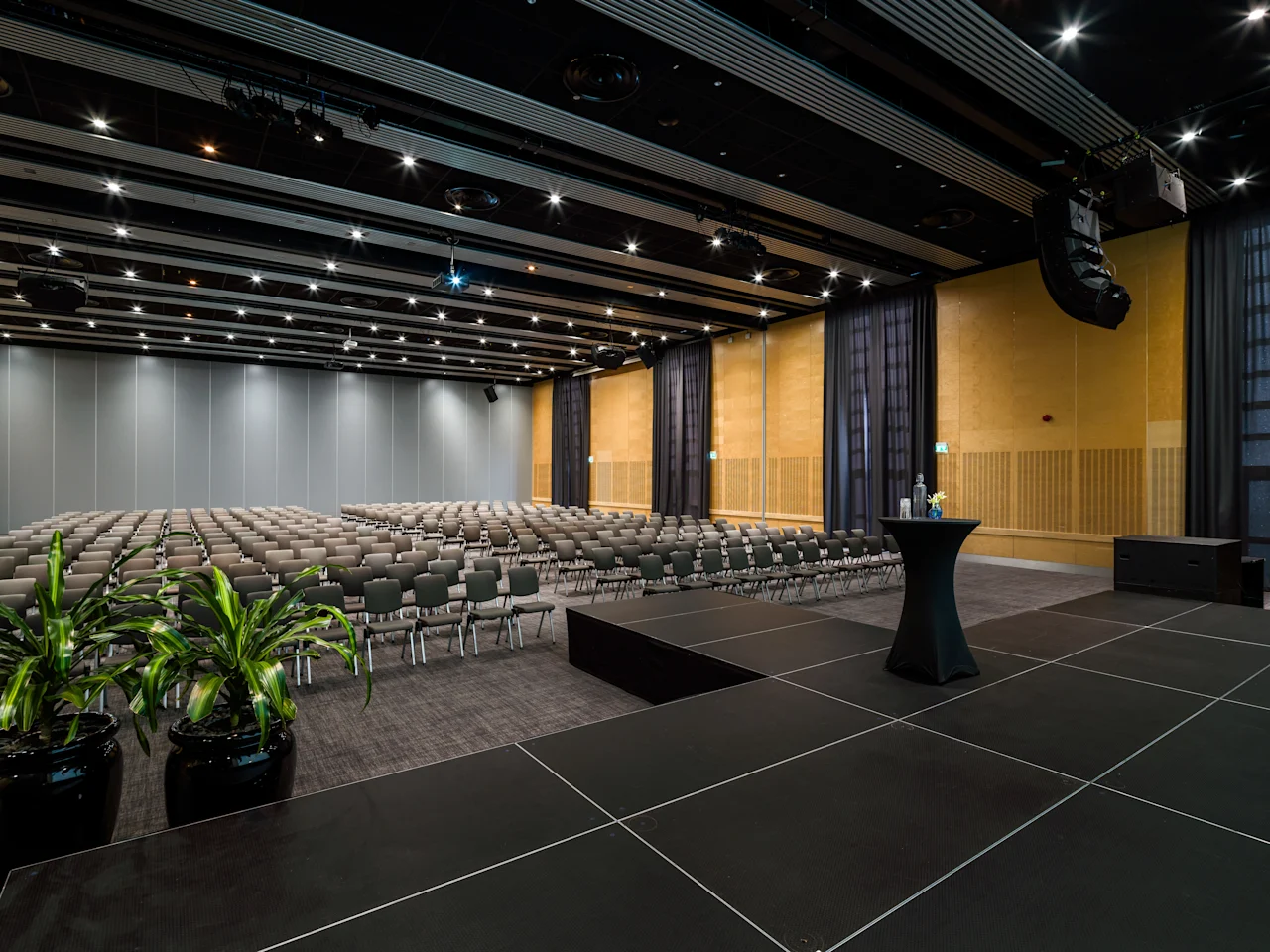 En modern hotellkonferenssal med rader av stolar vända mot en scen, redo för en presentation eller ett evenemang.