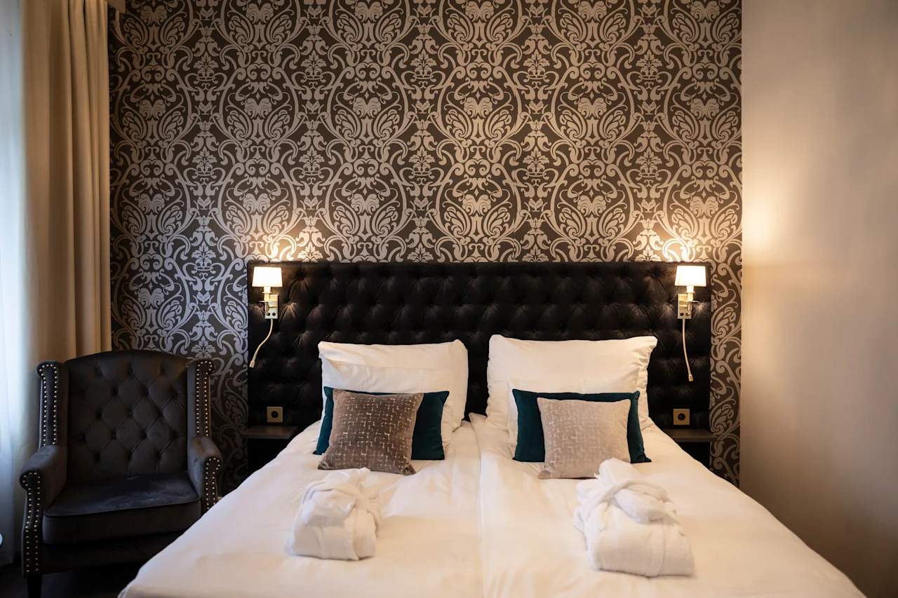 Et luksuriøst hotelværelse med en stor seng, bløde puder og bløde badekåber, der indbyder til et afslappende ophold.