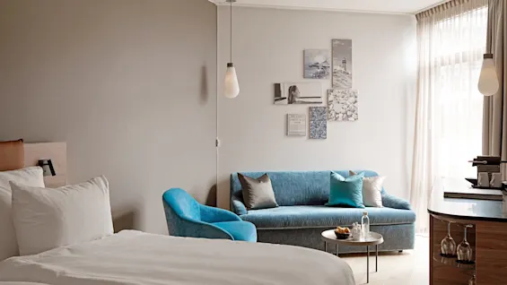 A comfortable hotel room at Farris bad in Larvik, featuring a bed, a blue sofa, and wall art with LARVIK OG BAD.