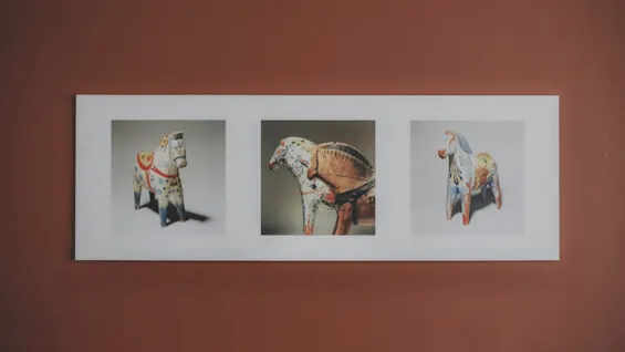 Three painted horse statues, each in an individual photo, are displayed on a white frame against a reddish-brown wall.