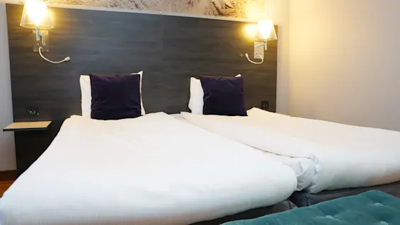 Viihtyisä hotellihuone Quality Hotel Sundsvallissa kahdella mukavalla sängyllä, valkoisilla liinavaatteilla ja lämpimällä valaistuksella.