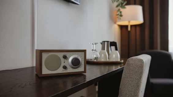 Hotelværelsets arbejdsplads med en klassisk radio med teksten Bluetooth og Model One, sammen med en bakke med glas.