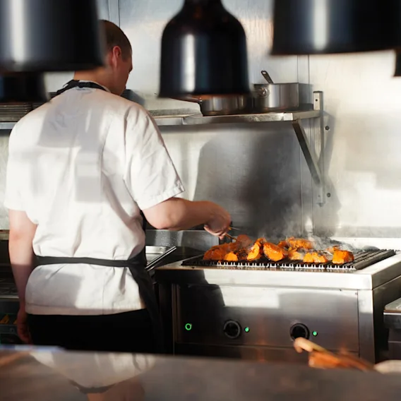 Kokki grillaa taitavasti ruokaa, höyryn noustessa, Restaurant NORin keittiössä Clarion Hotel Helsinki Airportissa.