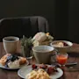 A delightful breakfast spread on a wooden table, featuring waffles, scrambled eggs, bacon, and various drinks. Home Hotel Post.