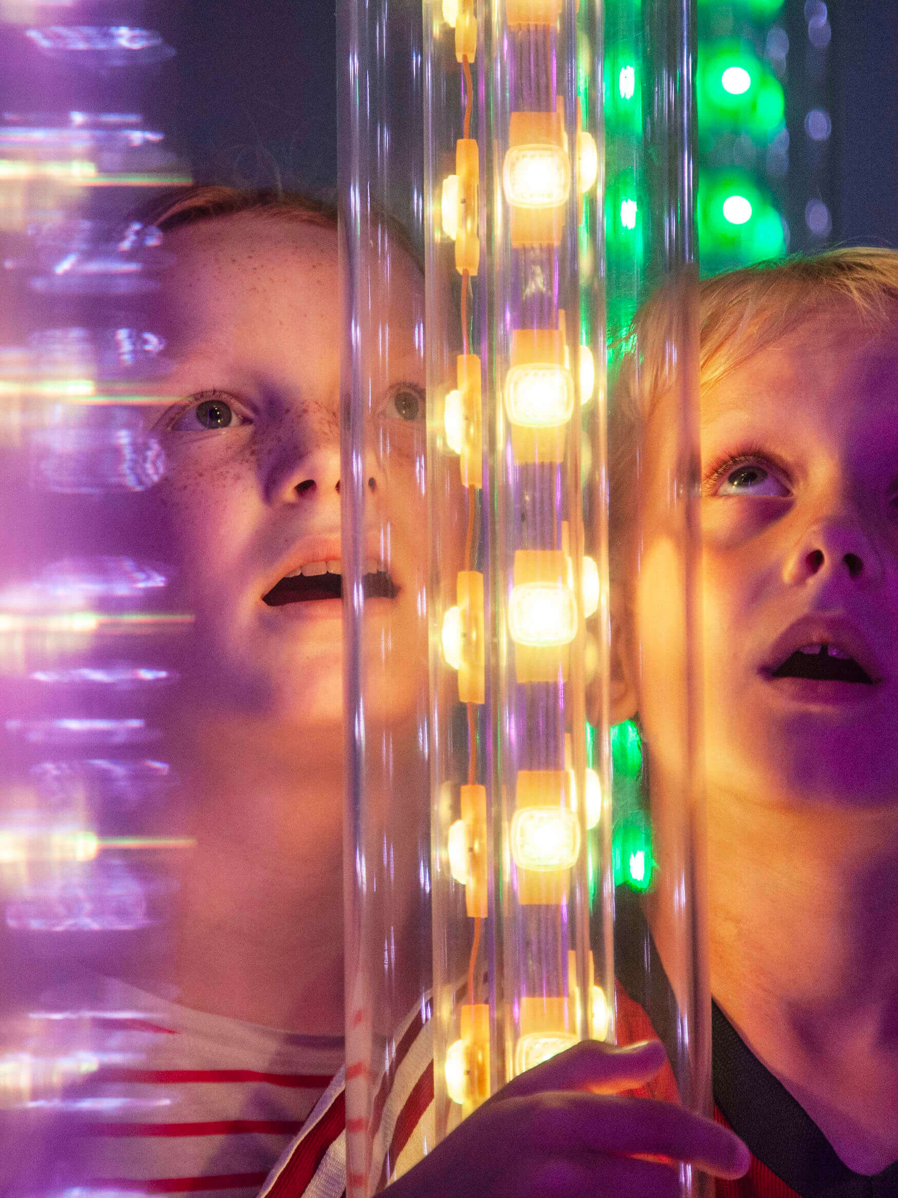 Kid looking at a glas wall filled with colors. 