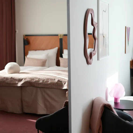 Moderne hotelværelse med en behagelig seng og et stilfuldt siddeområde opdelt af en skillevæg.