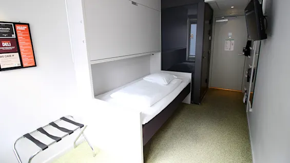 Kompakti ja moderni hotellihuone, jossa on yhden hengen sänky ja tyylikäs sisustus.