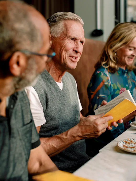 People at a restaurant, one holding a book.