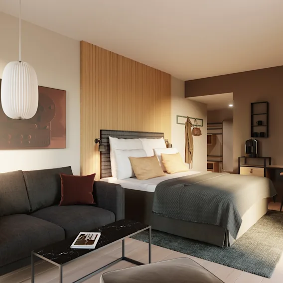 A modern hotel room with a comfortable bed, a cozy sofa, and a functional workspace, designed for relaxation and productivity.