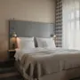 A cozy hotel room with a neatly made bed, bedside lamps, and striped curtains, ready for a comfortable stay.