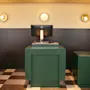 En modern reception med gröna diskar, en dator och cirkulära vägglampor, med ett rutigt golv.