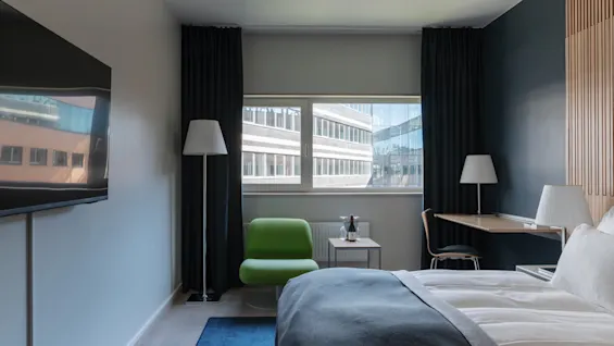 A modern and inviting hotel room at Clarion Hotel Sign, featuring a comfortable bed, a functional desk, and a bright window.