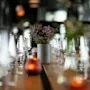 Et vakkert dekket spisebord med vinglass, en blomsteroppsats og varmt levende lys, som skaper en innbydende atmosfære.
