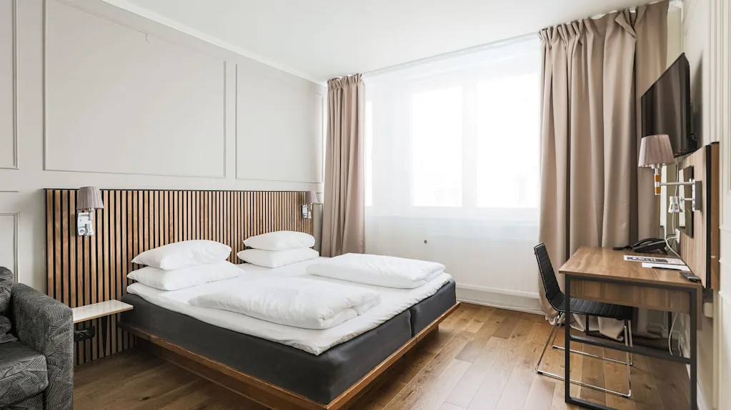 Et lyst og moderne hotellrom på Comfort Hotel Linköping City med en komfortabel seng, et skrivebordsområde og et stort vindu.