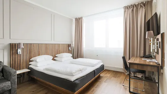 Valoisa ja moderni hotellihuone Comfort Hotel Linköping Cityssä mukavalla sängyllä, työpöytäalueella ja suurella ikkunalla.