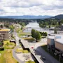 Et luftfoto av en by med en elv som renner gjennom den, omgitt av bygninger, veier og frodige grønne fjell.