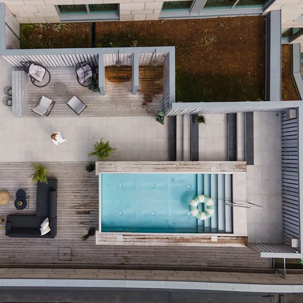 A person walks across a rooftop terrace with a swimming pool, outdoor furniture, and plants, seen from above.