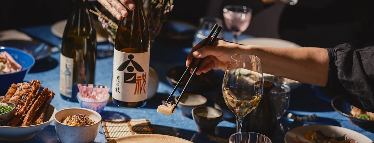 Et middagsbord på Clarion Hotel Post med ulike retter og drikke. En person bruker spisepinner for å plukke opp mat.