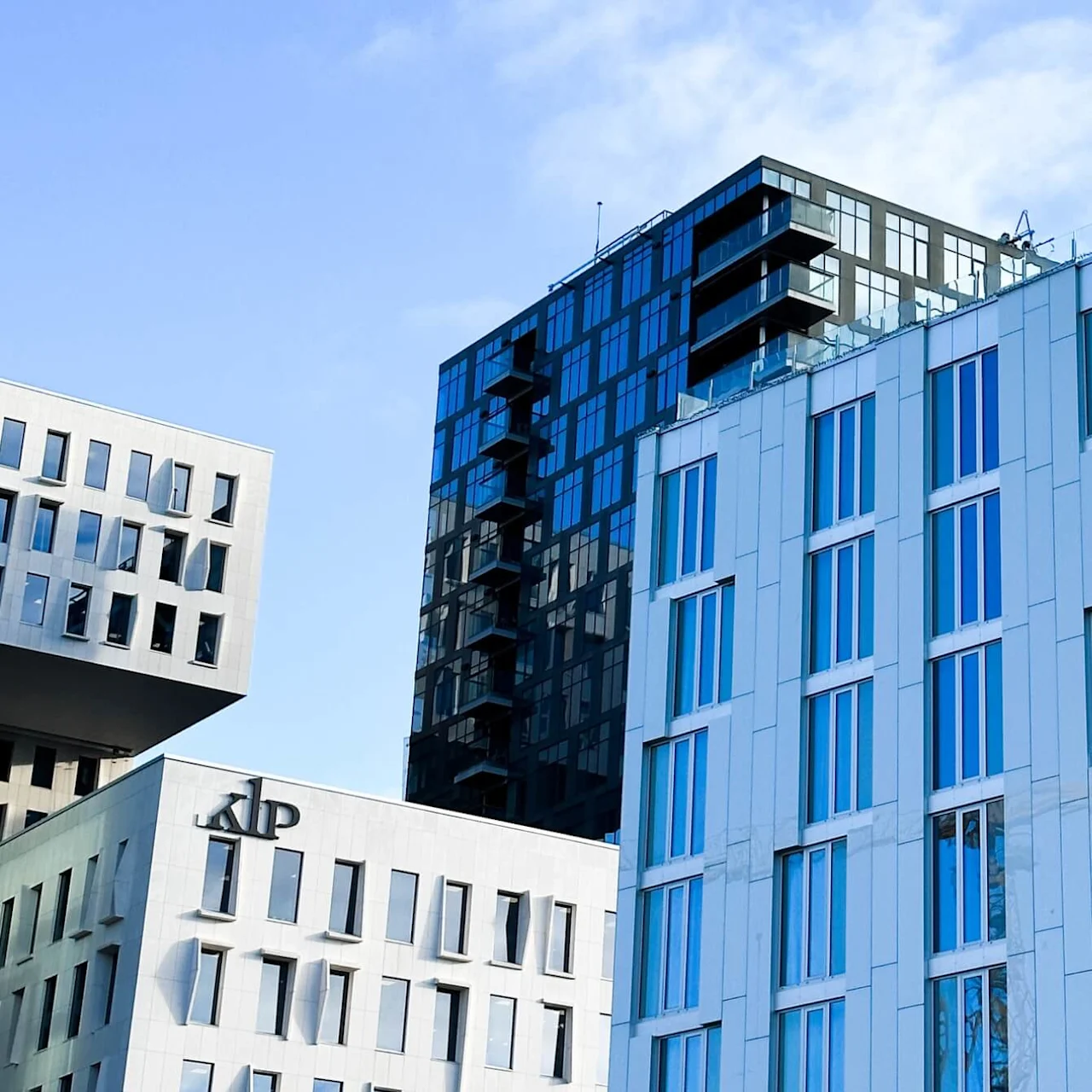 A modern building with blue-tinted windows displays the vertical text "CLARION HOTEL OSLO" in an urban skyline, next to another building with "KLP" logo.