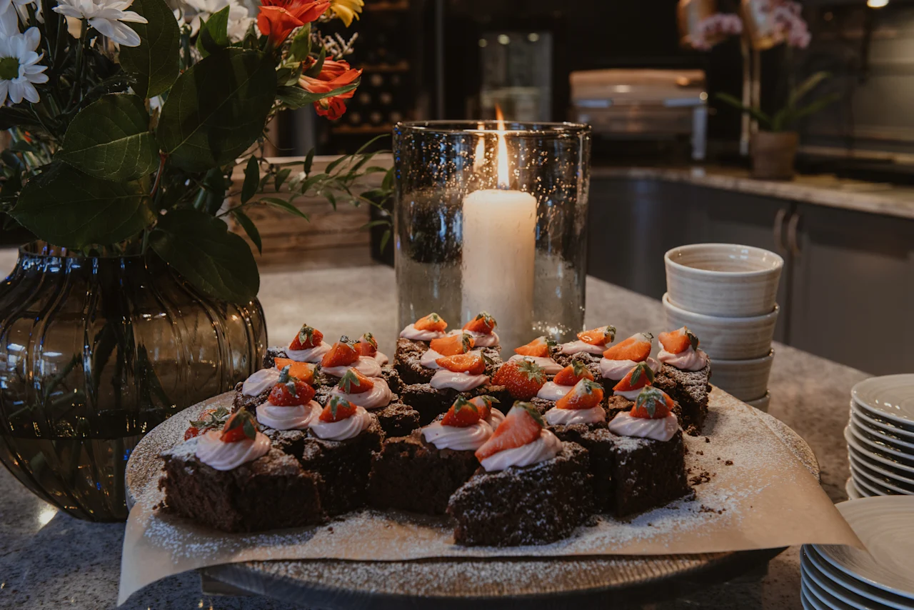 Home Hotel Kung Oscar. Delicious brownies with strawberry topping and a lit candle create a warm, inviting dessert scene.