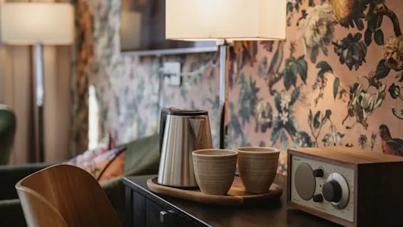 Et indbydende hotelværelse på Home Hotel Norre Park, med en te- og kaffestation og en radio på en mørk træoverflade.