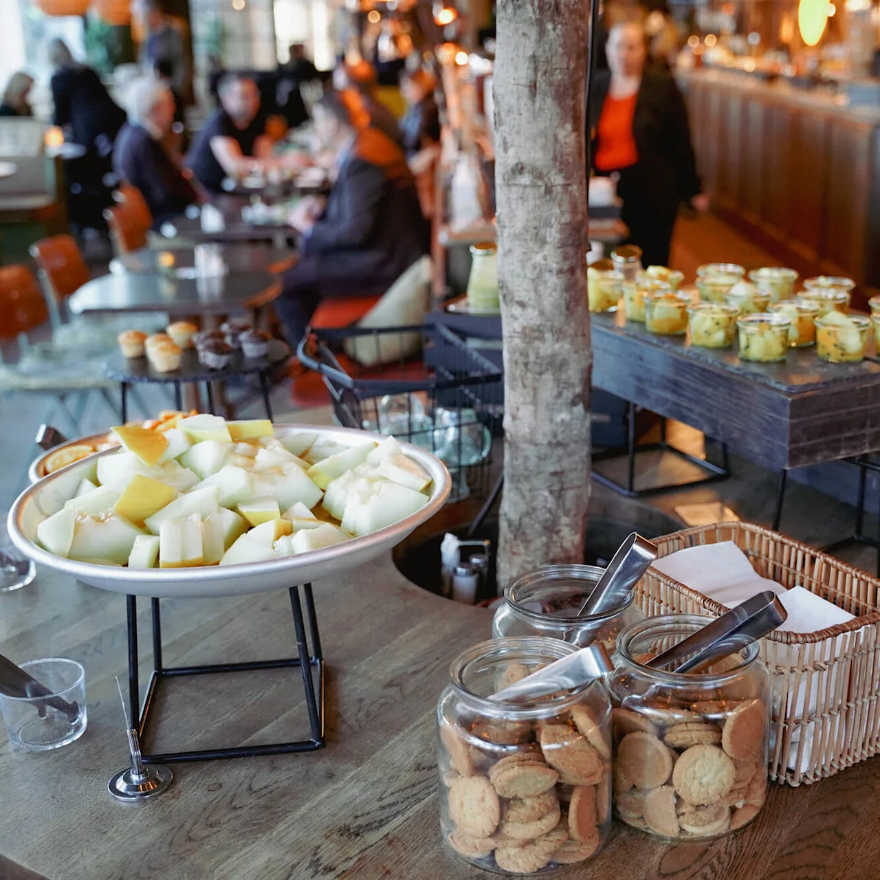 Forskellige fødevarer udstillet på borde i en livlig restaurant.