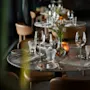 Et elegant dekket restaurantbord med vinglass, vannglass, bestikk, servietter, blomster og et varmt lys.