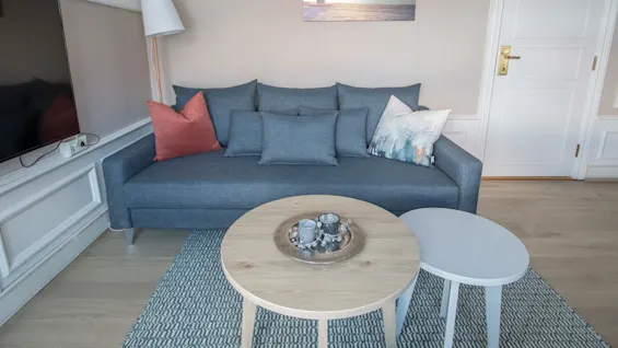 En komfortabel stue med en blå sofa, salongbord og en TV, som skaper et innbydende sted for avslapning.