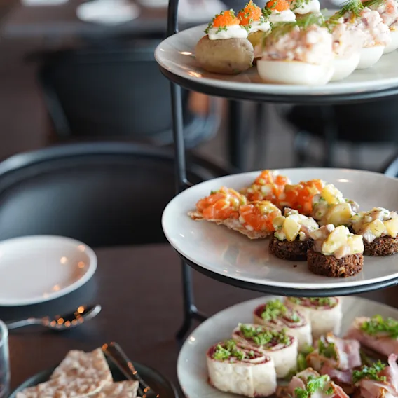 Ett trevåningsfat fyllt med ett urval av läckra aptitretare och små tilltugg, redo att avnjutas i en restaurangmiljö.