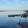 En rolig havnescene med stille vann, båter fortøyd ved en brygge og en fjern øy, som gjenspeiler den fredelige atmosfæren på Quality Hotel Öresund i Landskrona.