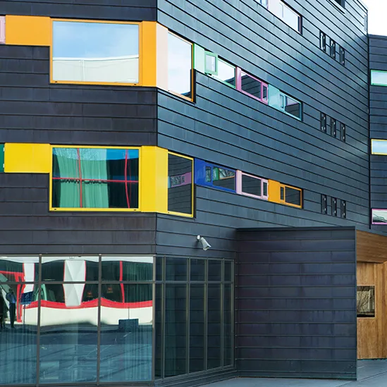 A modern hotel building has colorful windows set in dark, paneled walls. The sign reads "COMFORT HOTEL RUNWAY." A parked car is visible in front.