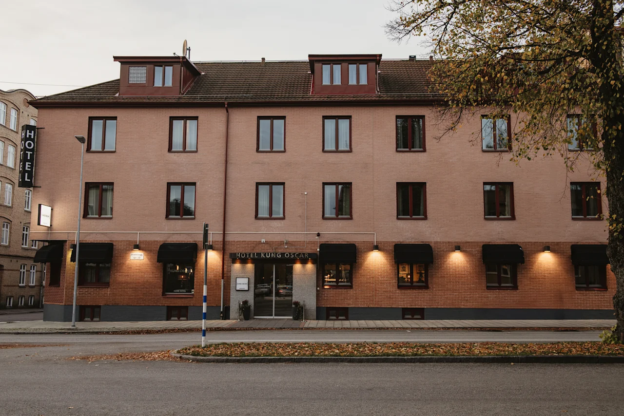 Home Hotel Kung Oscar. A brick hotel building with black awnings and a sign that says Hotel.