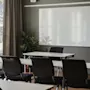 Ett ljust mötesrum med rader av bord och stolar vända mot en stor whiteboard. Ett fönster med gardiner finns till vänster.