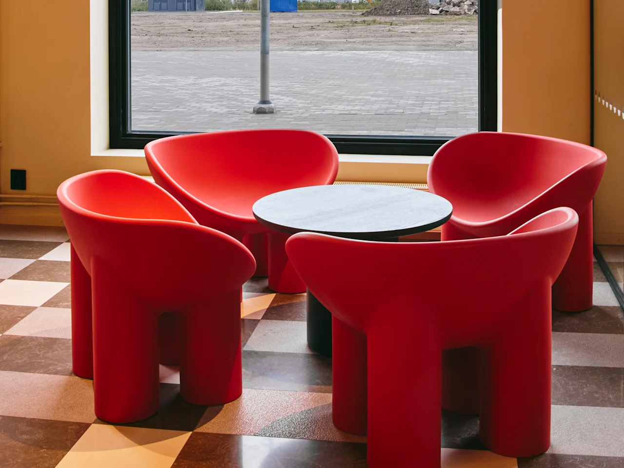 Et koselig sitteområde med fire moderne røde stoler og et lite bord, perfekt for en avslappende mellomlanding på Hotell Falkenberg.