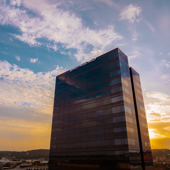 A tall modern hotel building standing against a beautiful sunset sky with soft clouds