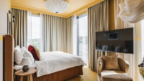Et lyst og indbydende hotelværelse på Hernö Gin Hotel med en komfortabel seng, TV og en naturskøn udsigt.