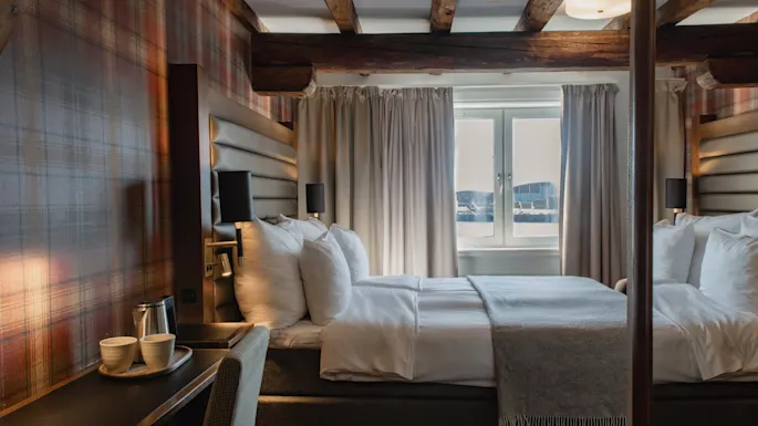 Et innbydende hotellrom med en komfortabel seng, en varmrutete vegg og en naturskjønn utsikt over vannet.