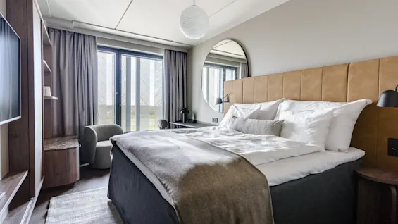 Et komfortabelt og moderne hotelværelse med en stor seng, et vindue og et siddeområde.
