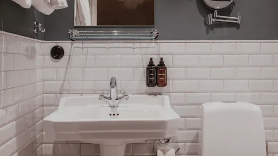 Home Hotel Baltzar - Family Room. A classic bathroom with a white pedestal sink, toilet, mirror, and subway tiles.