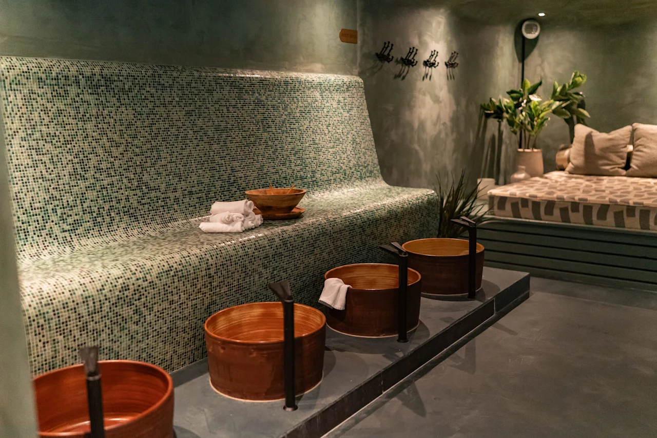Rauhallinen kylpylähuone mosaiikkilaatoitetulla penkillä, jalkakylvyillä ja mukavalla oleskelualueella rentoutumiseen.