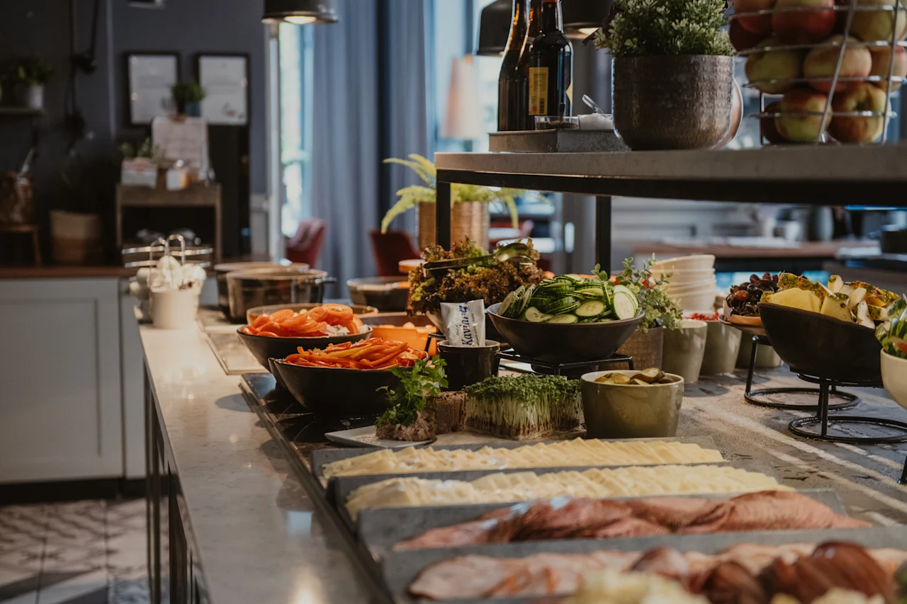 En fargerik buffet med friske salater, skivet kjøtt, oster og frukter, med en liten pakke merket kaviar.