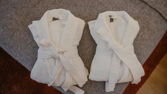 Two cozy white bathrobes folded on a bed, ready for relaxation at Home Hotel Kung Oscar.